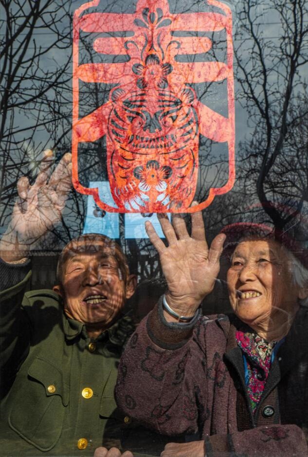 臘月里，霍州市師莊鄉(xiāng)馮南垣村村民師榮光(左)在災(zāi)后重建的新家里貼窗花。(霍州市委宣傳部供圖)