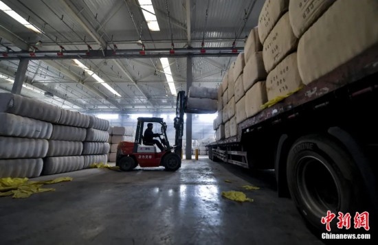 新疆喀什綜合保稅區(qū)，喀什啟路國際貿(mào)易有限公司的倉庫內(nèi)，工人正在裝載從塔吉克斯坦和烏茲別克斯坦進(jìn)口的棉花。劉新攝