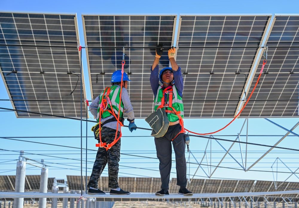 2023年7月22日，工人在位于內(nèi)蒙古杭錦旗庫布其沙漠億利生態(tài)示范區(qū)的蒙西基地庫布其200萬千瓦光伏治沙項目工地安裝光伏板。新華社記者 劉磊 攝
