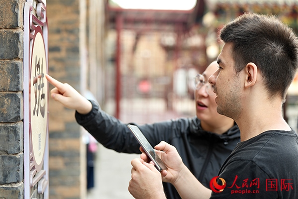 選手安德烈（俄羅斯）在老師指導(dǎo)下學(xué)習(xí)墻壁上張貼的生僻字。人民網(wǎng) 盧鵬宇攝