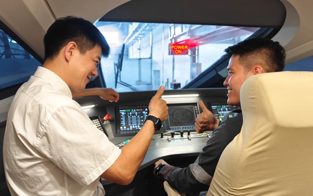 8月25日，在印度尼西亞萬隆的雅萬高鐵德卡魯爾動車所內(nèi)，中國師傅穆振（左）在向印尼火車司機(jī)塞蒂亞萬講解動車組出庫前的上電作業(yè)。