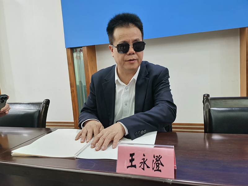 全國人大代表王永澄正在閱讀盲文版代表建議答復(fù)。本報記者 張 璁?dāng)z