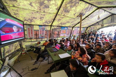 12月22日，在積石山縣大河家鎮(zhèn)大河村安置點(diǎn)，陸軍76集團(tuán)軍某旅搭建的“臨時(shí)學(xué)?！眱?nèi)，小朋友正在看動(dòng)畫片。人民網(wǎng)記者 翁奇羽攝