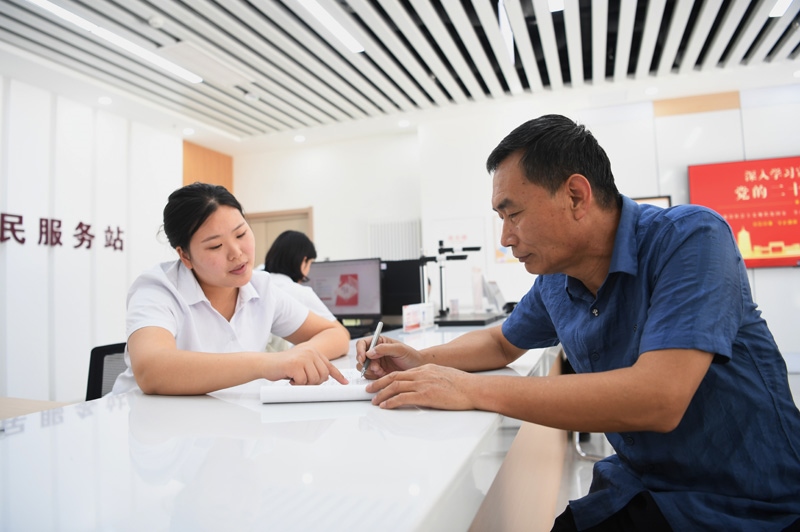 2023年5月23日，河北雄安新區(qū)容東片區(qū)南文營(yíng)社區(qū)居民（右）在社區(qū)便民服務(wù)站辦理業(yè)務(wù)。