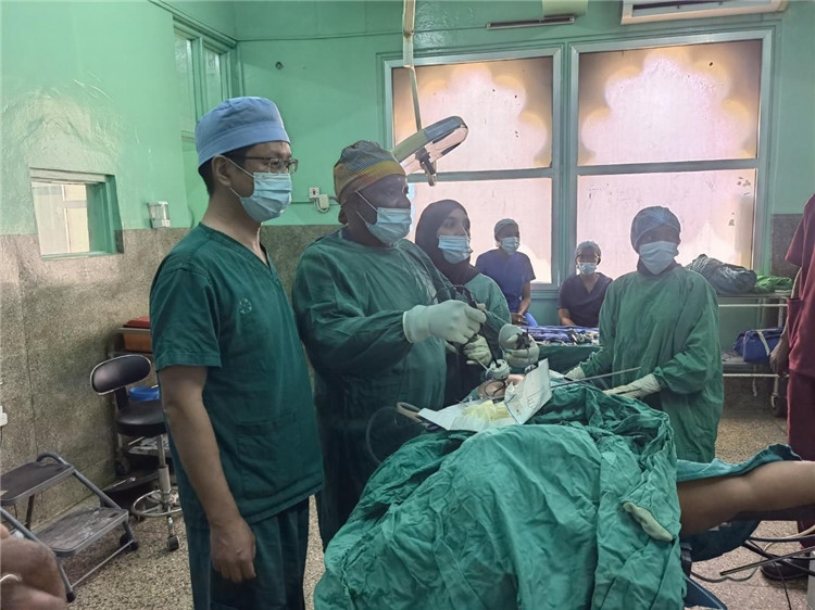 隊長蔣國慶（左一）關注當?shù)蒯t(yī)生手術情況。中國援桑醫(yī)療隊供圖