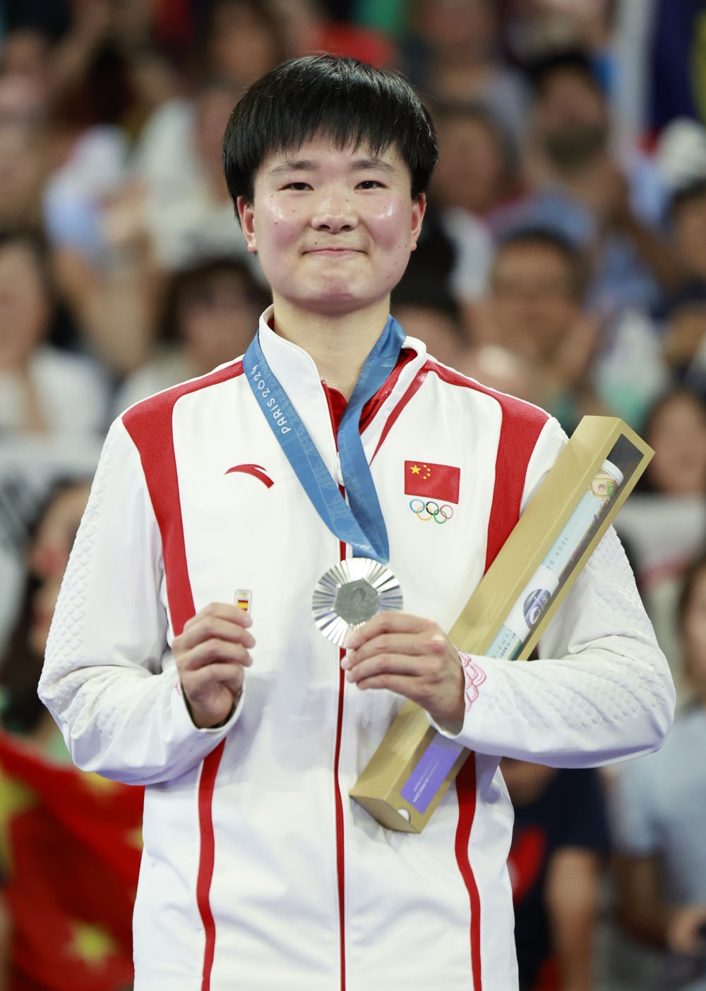 巴黎奧運(yùn)會(huì)羽毛球女子單打亞軍、中國(guó)選手何冰嬌在頒獎(jiǎng)儀式上一手握著銀牌，一手握著西班牙奧委會(huì)徽章（2024年8月5日攝）。新華社記者 任正來(lái) 攝